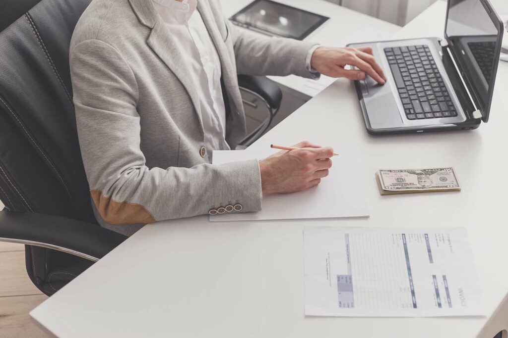 Manufacturing accountant uses PC in his office to calculate payroll for employees