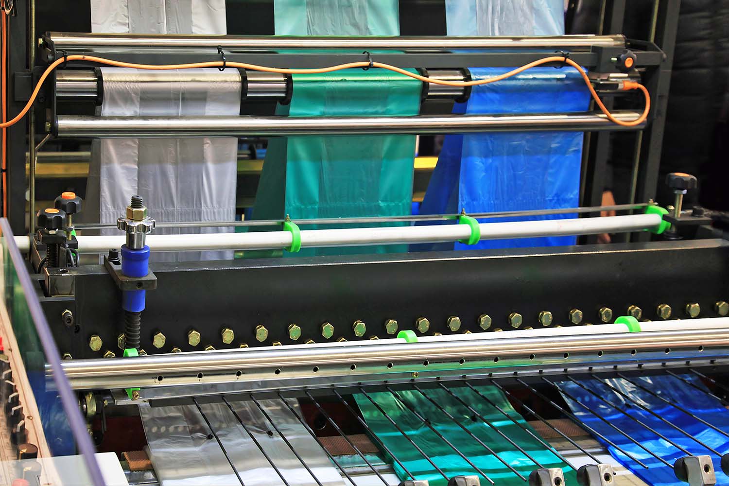 rolls of multiple colored plastic bags on a production machine at a plastic manufacturing company representing the chemical & plastics industries
