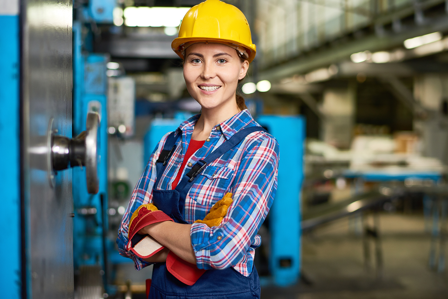 Happy female factory worker in the quality management area of a manufacturing factory